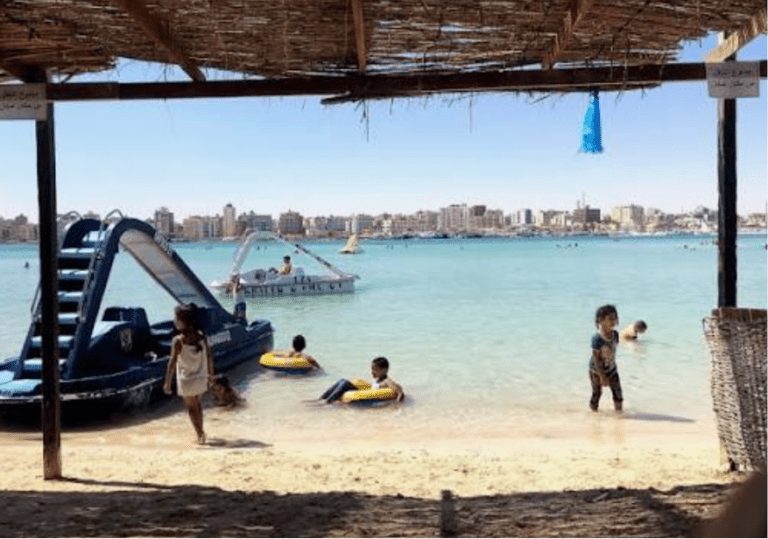 Family swimming in clear turquoise water at Marsa Matrouh on Egypt's Mediterranean Coast.