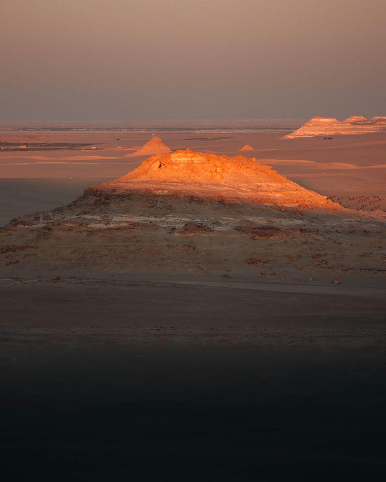 A captivating view of the Siwa Oasis desert at sunset, highlighting the illuminated mountain formations.