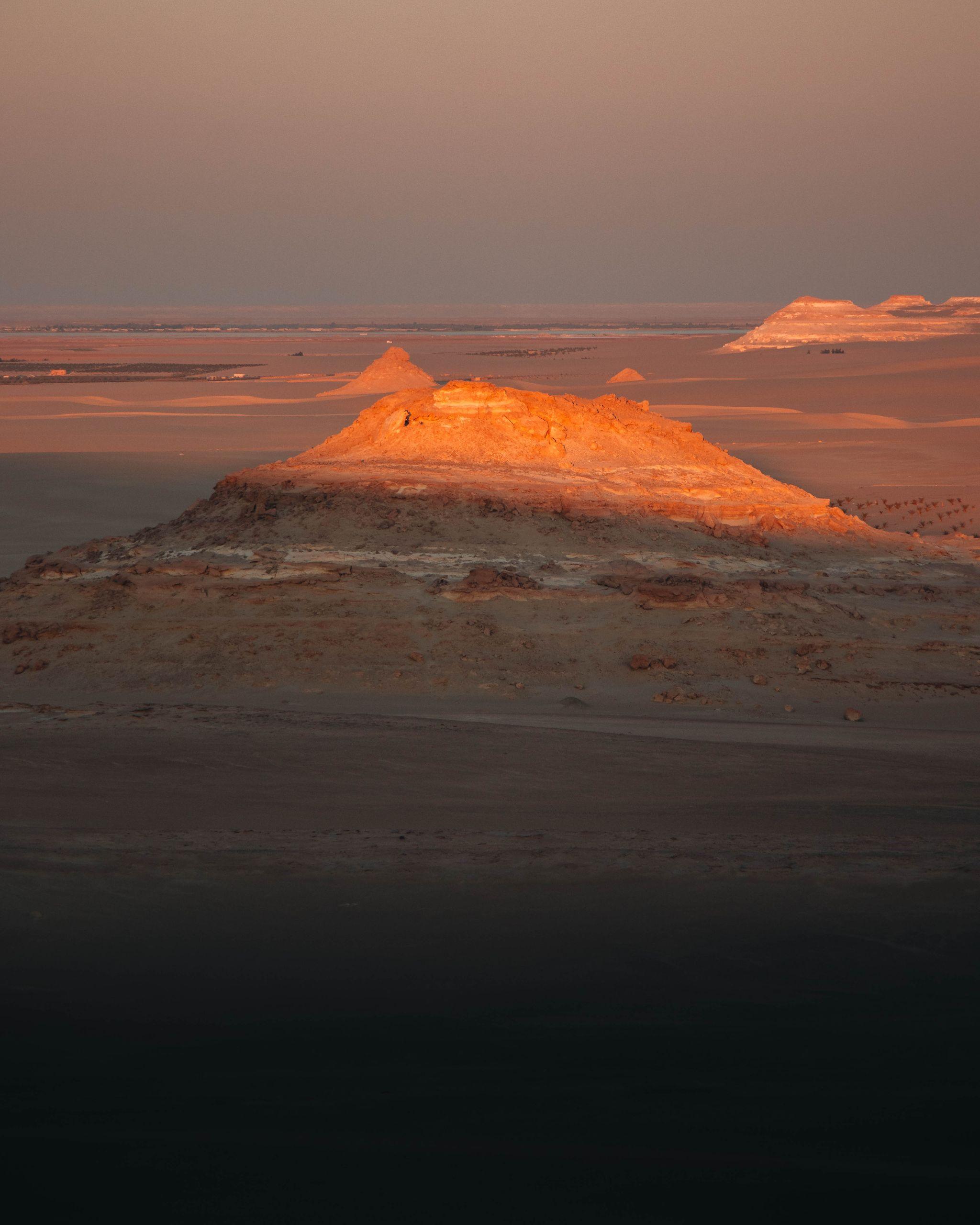 A captivating view of the Siwa Oasis desert at sunset, highlighting the illuminated mountain formations.