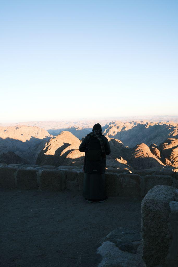 A contemplative moment as a person overlooks Mount Sinai's rugged beauty at dawn.