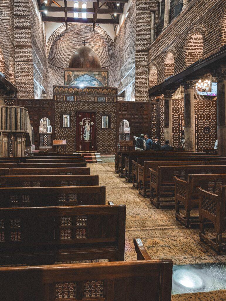 Explore the serene interior of a historic church in Coptic Cairo, Egypt, showcasing intricate brickwork and architectural beauty.